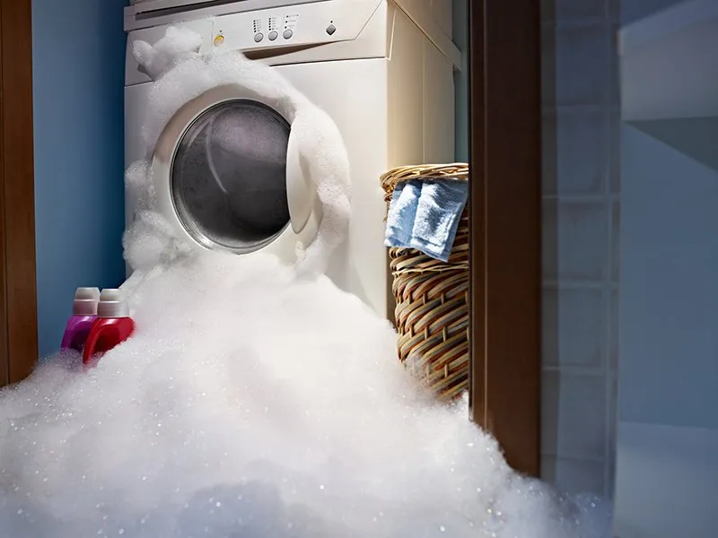 Washing machine overflowing with suds — real appliance breakdown in a laundry room