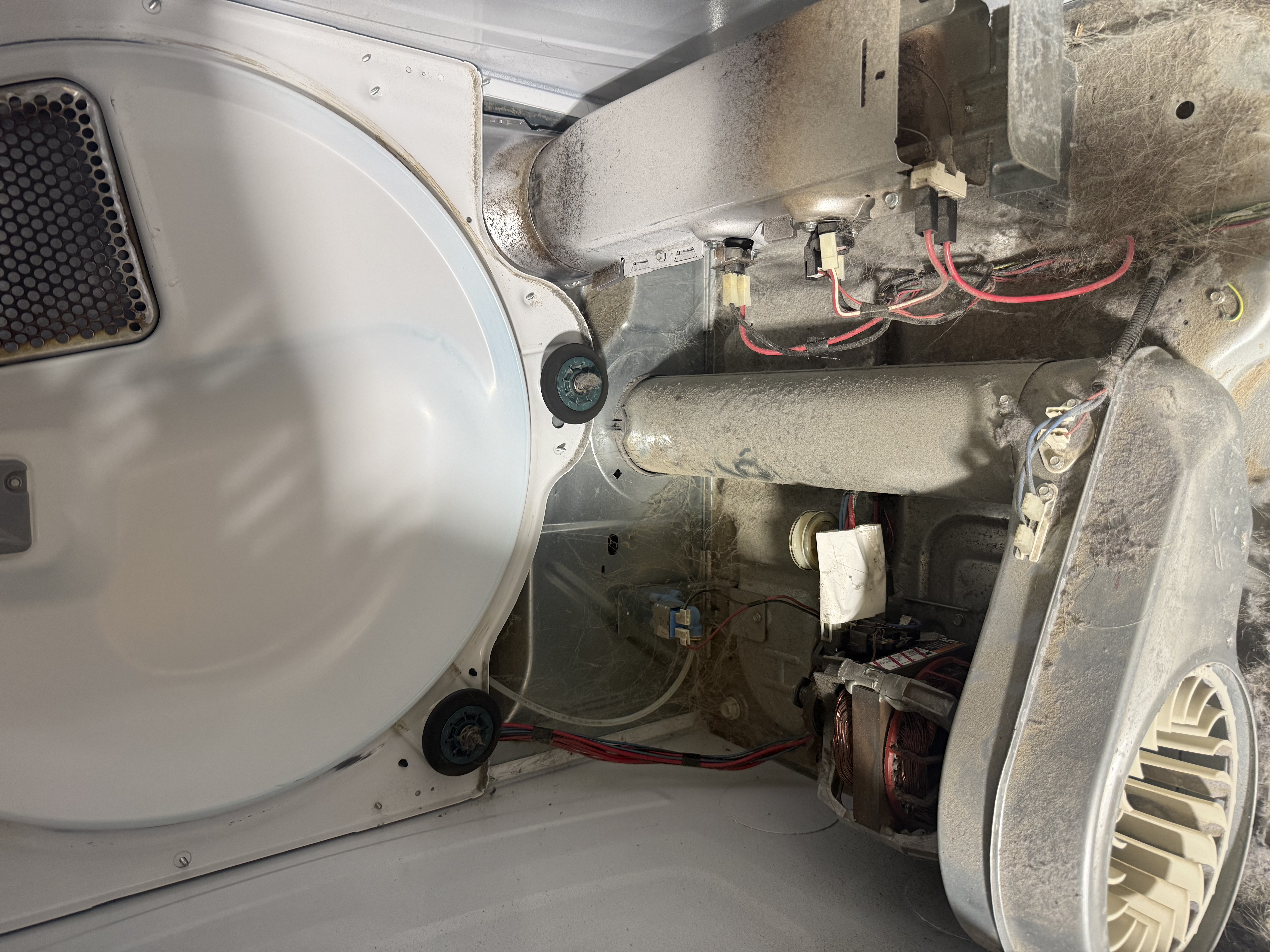 Dryer interior before cleaning showing heavy dangerous lint buildup around the blower and motor