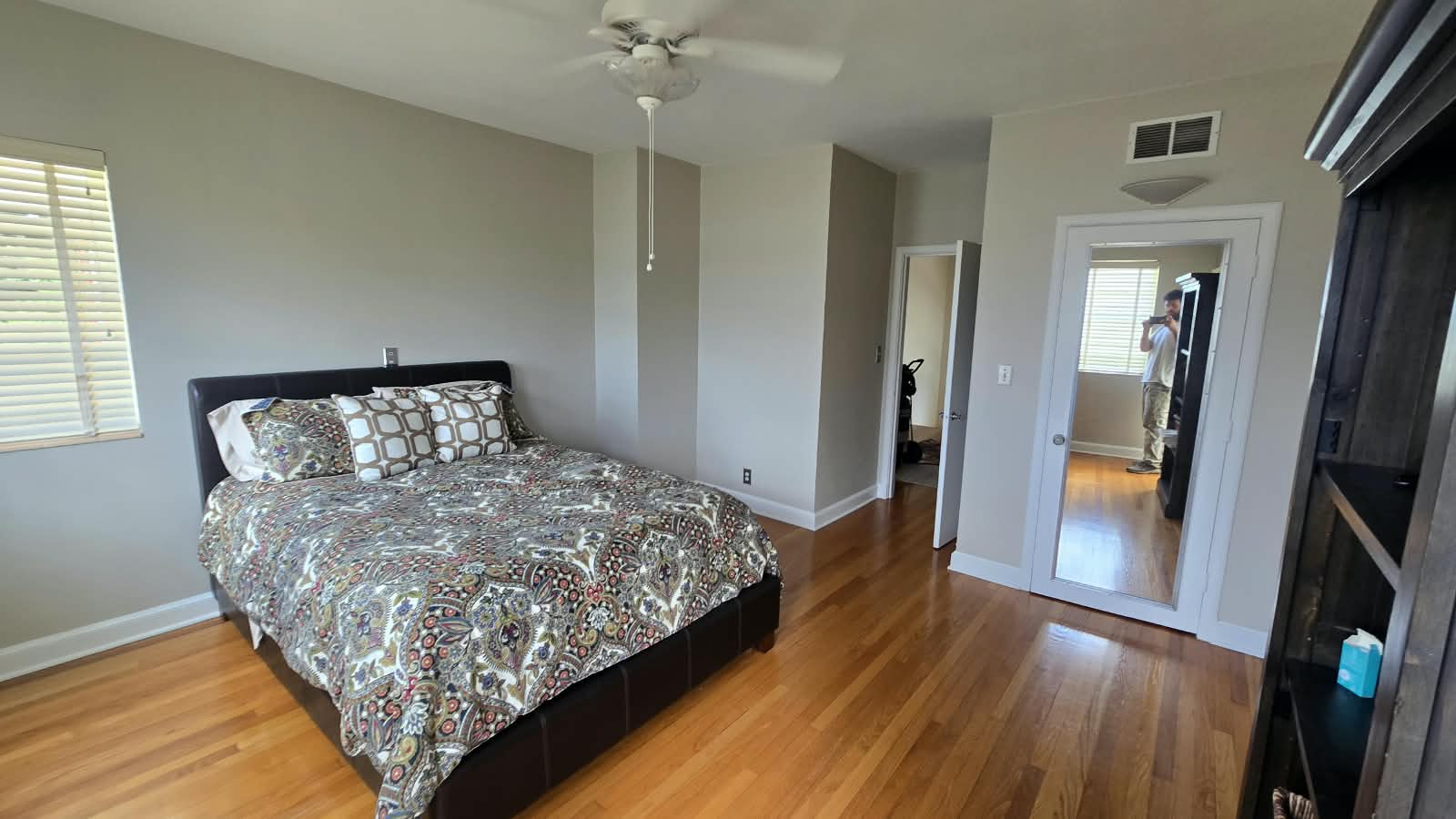 Completed bedroom interior repaint with clean neutral walls, crisp white trim, and hardwood flooring