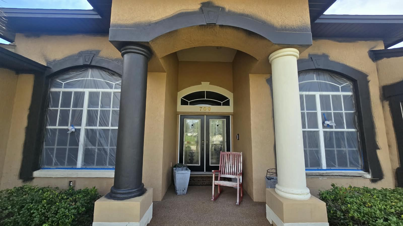 Front entry portico during surface prep with masked windows and cut-in arch trim