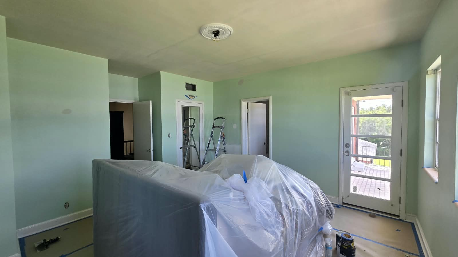 Interior bedroom with fresh walls, furniture plastic wrapped and floors protected