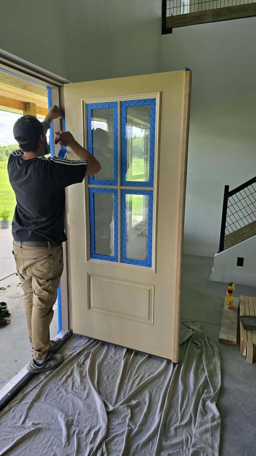 Fine Line painter meticulously taping multi-lite craftsman entry door for spray finish