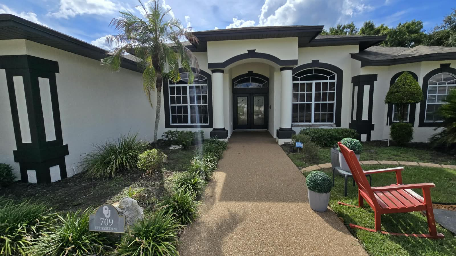 Completed front entryway and walkway on Florida stucco home with dark contrasting arch trim