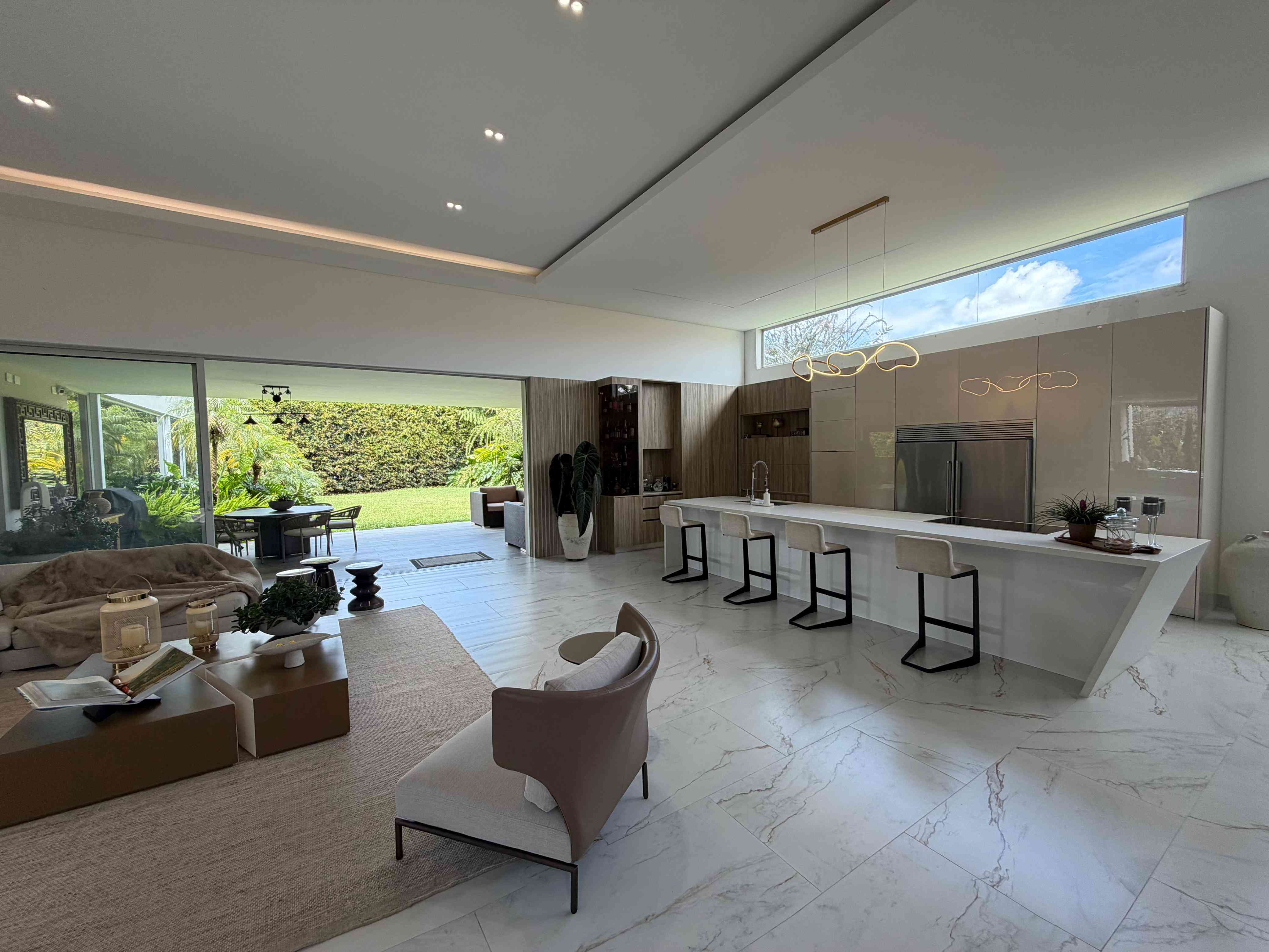 Gran sala a doble altura integrada con cocina contemporánea y vista panorámica a la terraza y jardín