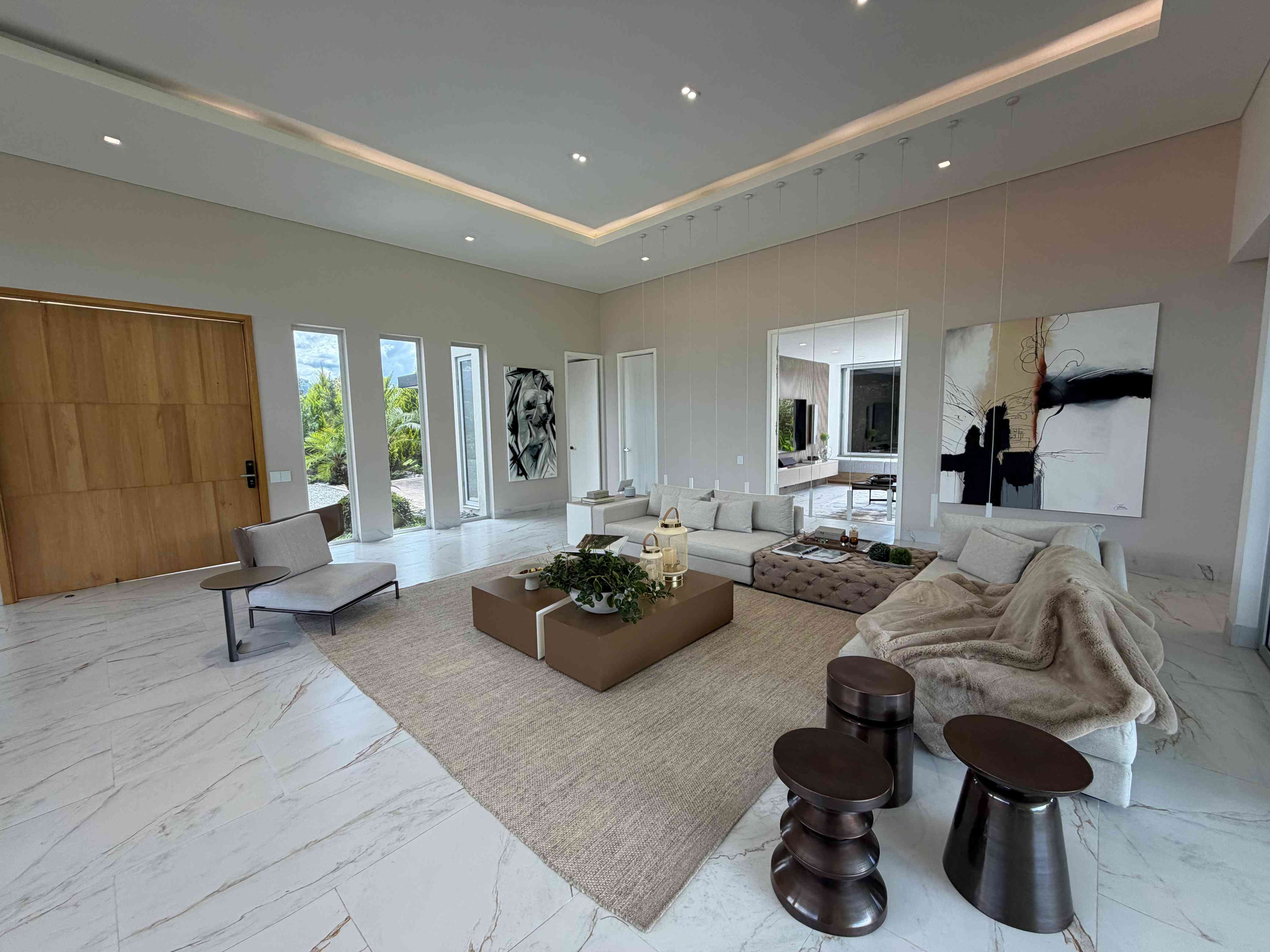 Sala principal a doble altura con pisos de mármol y ventanales panorámicos