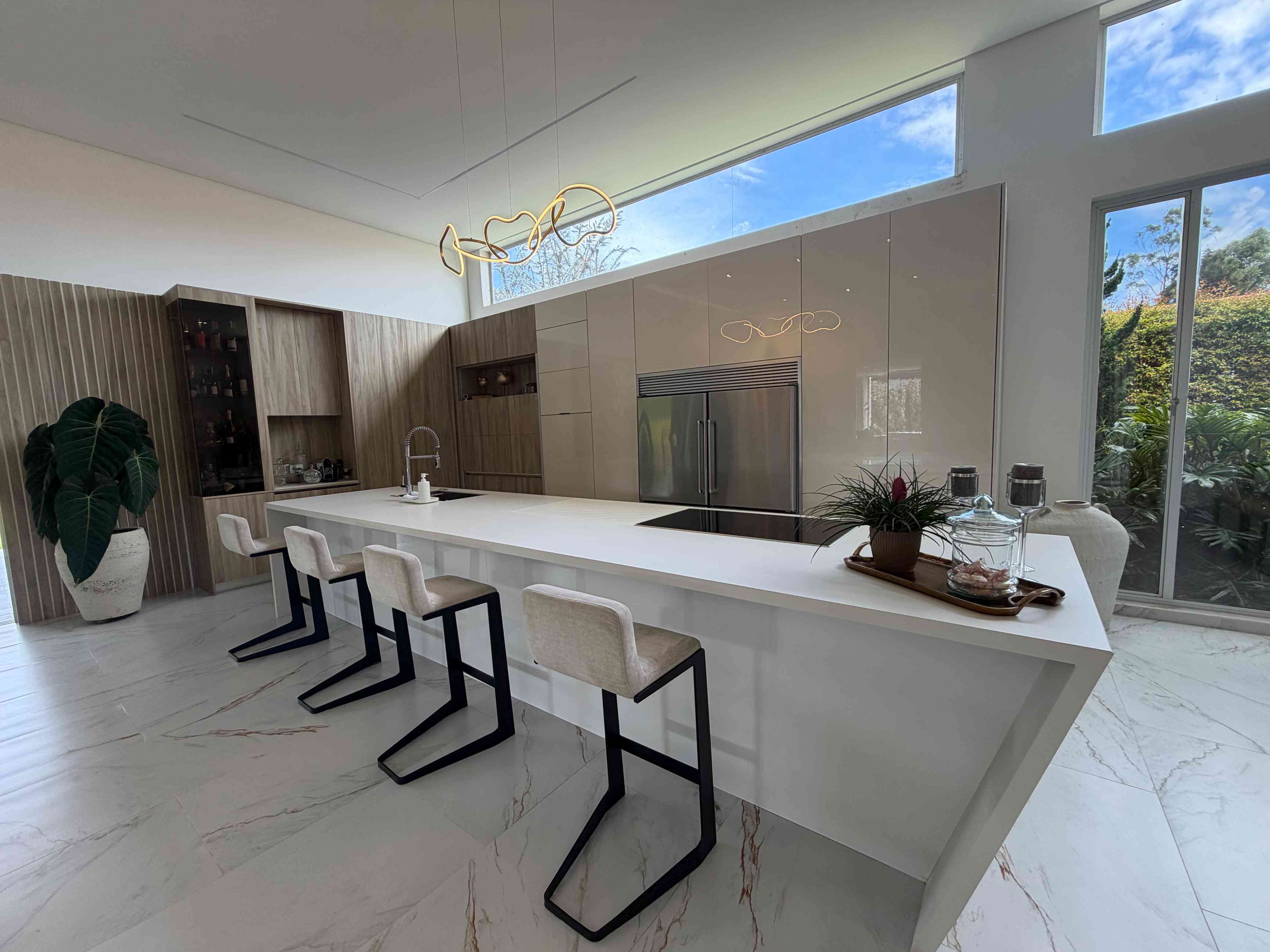 Isla de cocina con barra, acabados de alta gama y luminaria escultural suspendida