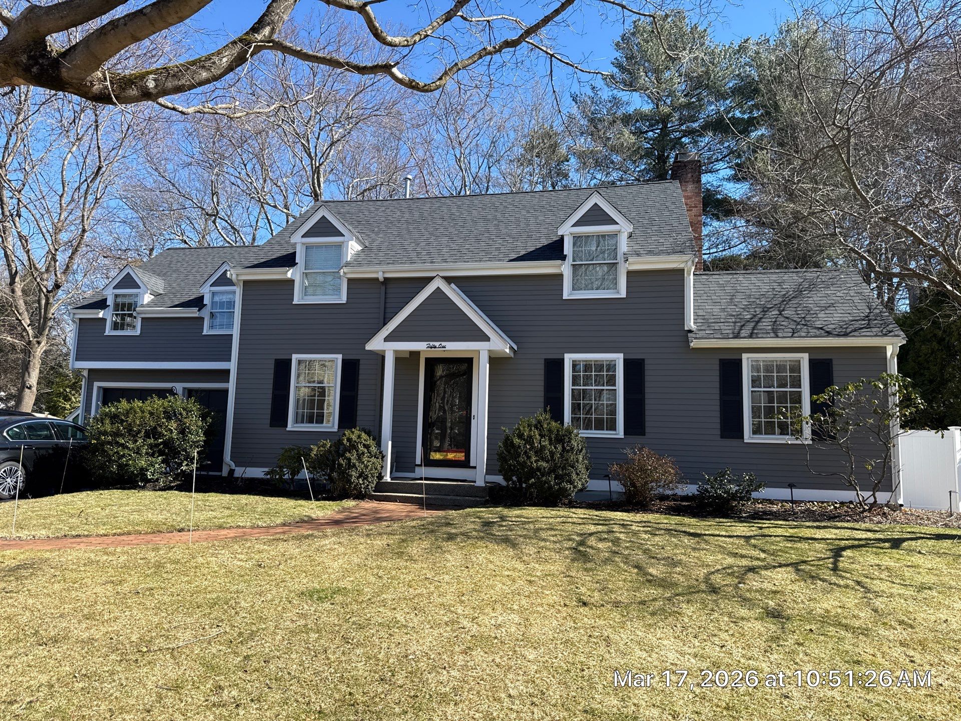After siding replacement: completed deep charcoal horizontal siding with crisp white dormer trim, black shutters, and finished entry portico