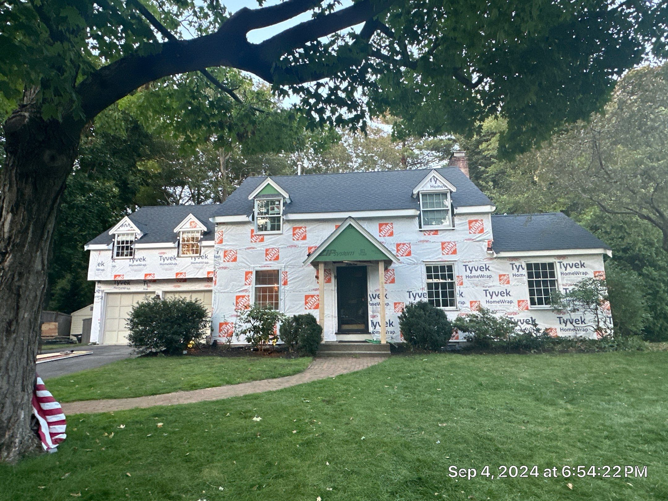Before siding replacement: Massachusetts home with full weather barrier wrap and framed portico entry awaiting new siding