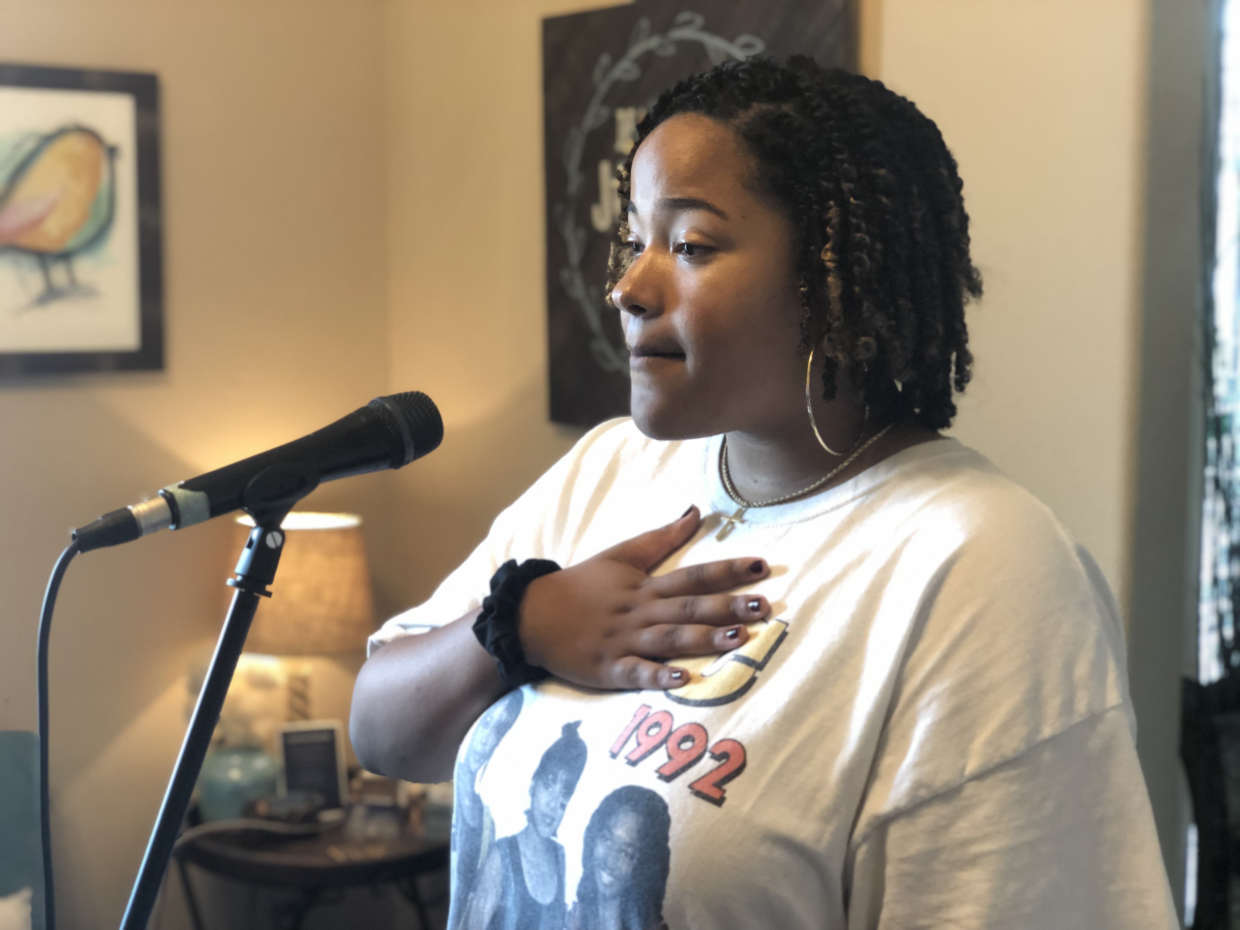 Vocal Edge student singing at the microphone with hand on chest practicing technique