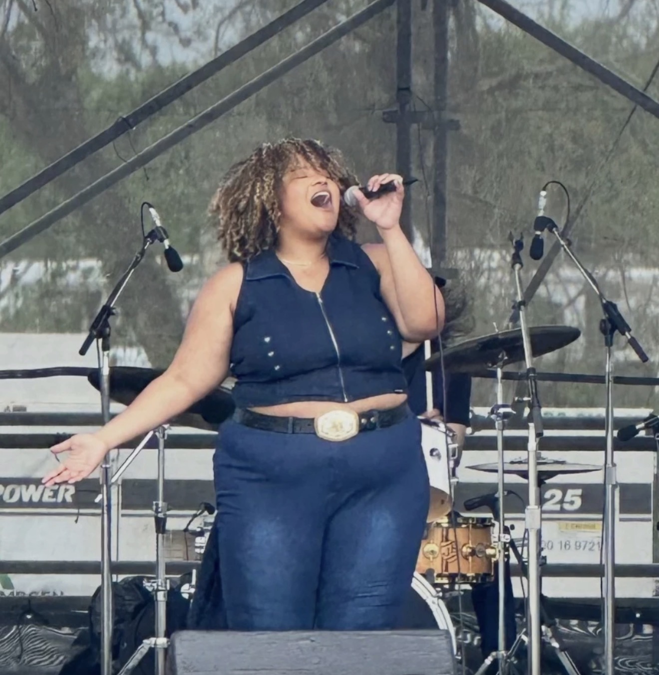 Michaela Watson singing passionately on stage into a microphone