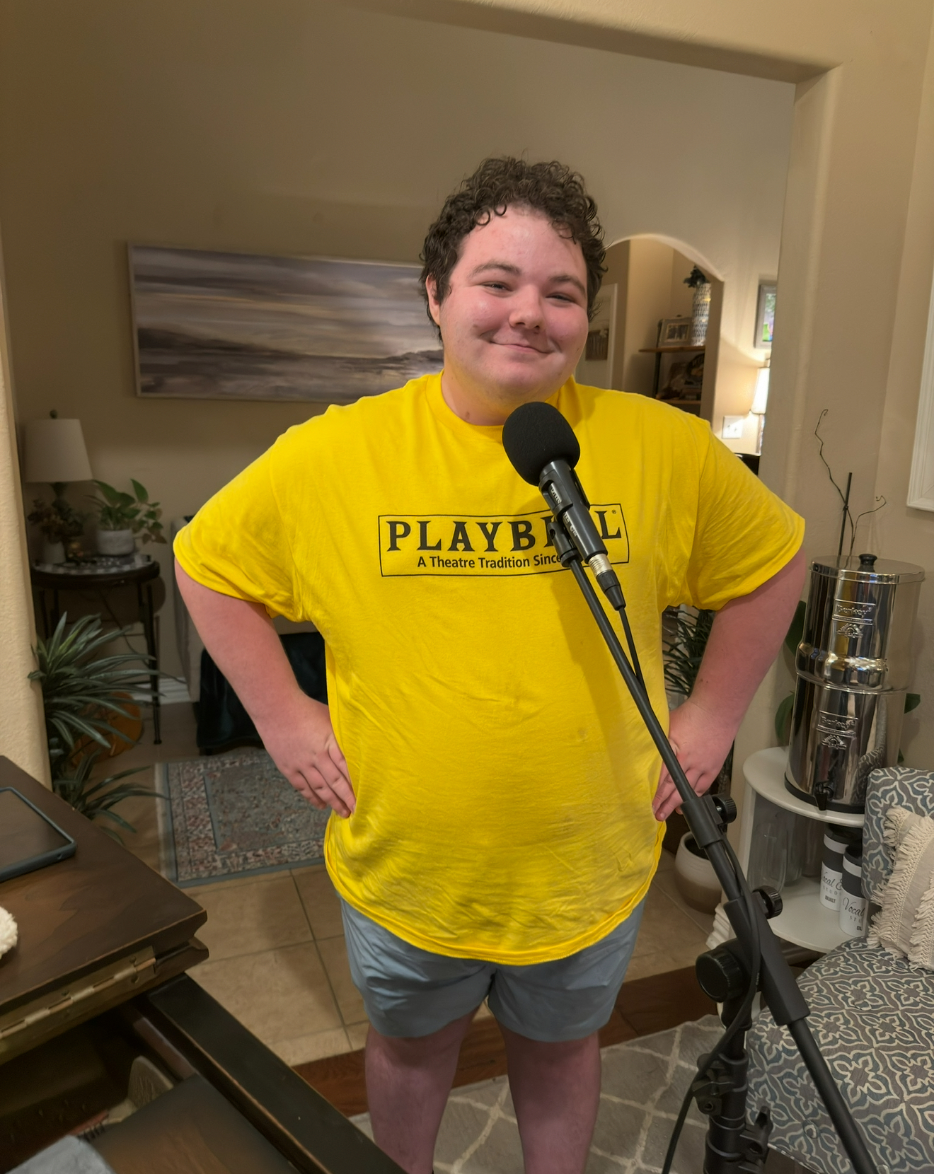 Eli Johnson-Bell smiling by the microphone in a Playbill shirt, winner of the lead role in Putnam County Spelling Bee