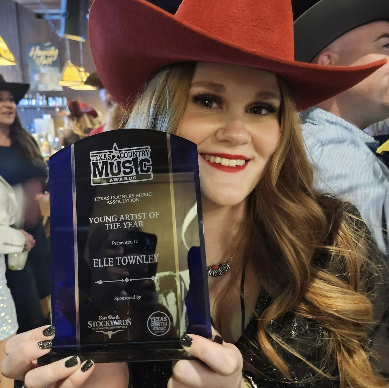 Elle Townley in red cowboy hat holding her Texas Country Music Association Young Artist of the Year award
