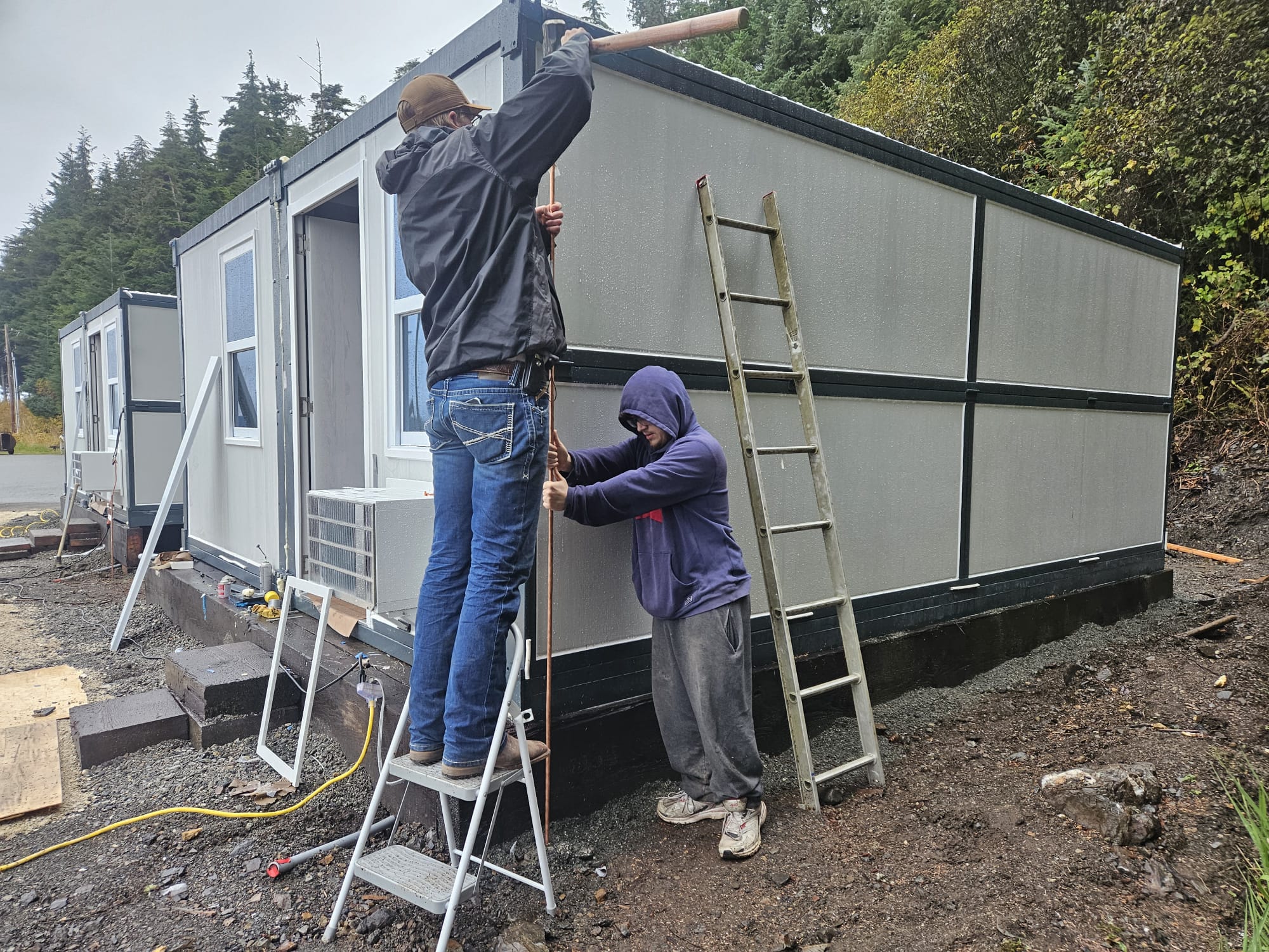 Field assembly crew raising foldable modular microshelter walls on site