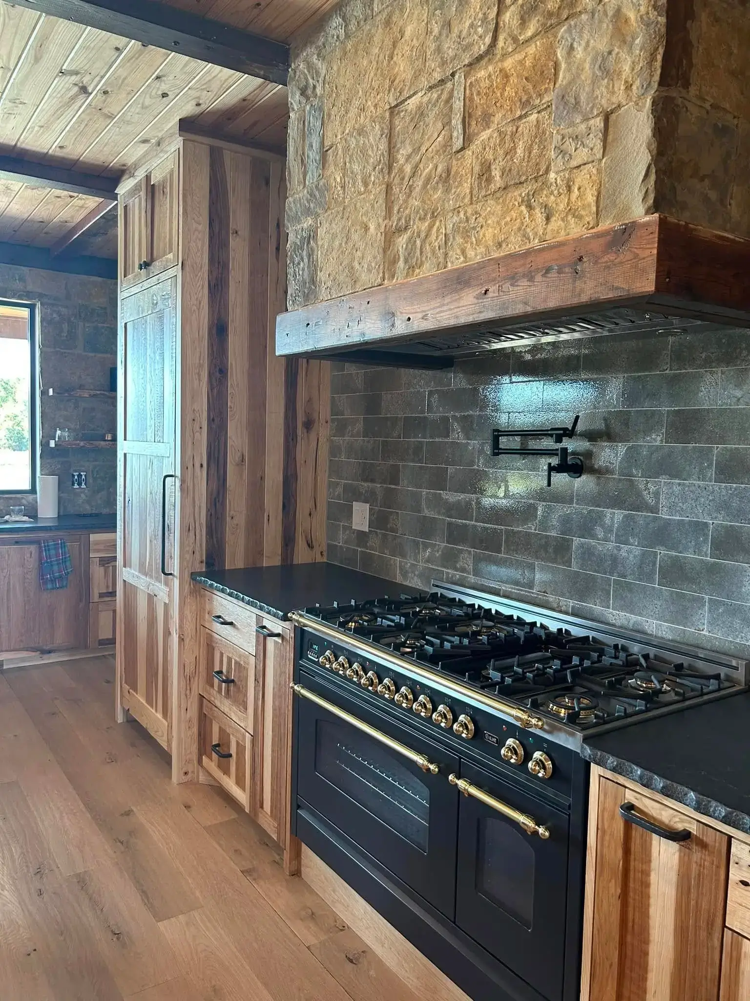 Luxury custom kitchen remodel with natural stone range hood, tile backsplash, and handcrafted cabinetry