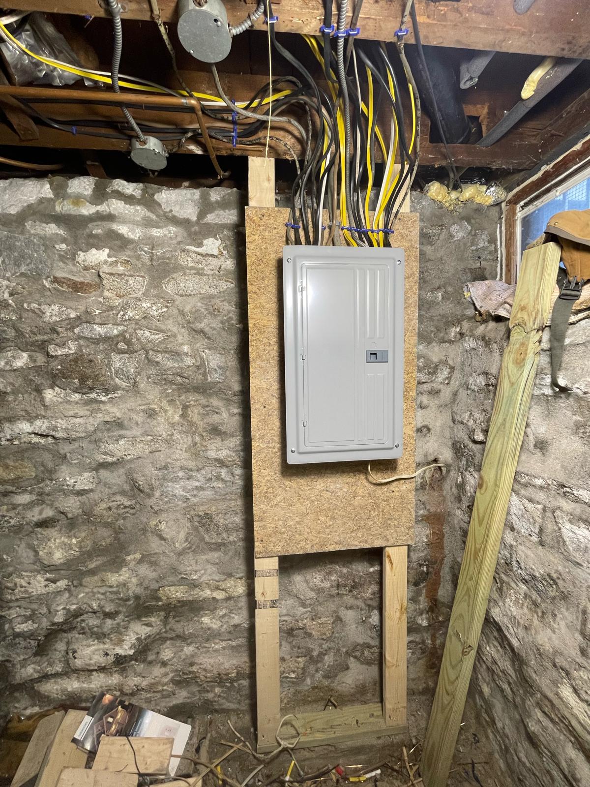 Finished grey breaker load center mounted on custom wood frame in fieldstone basement by Prime Light Electric LLC in Holden MA