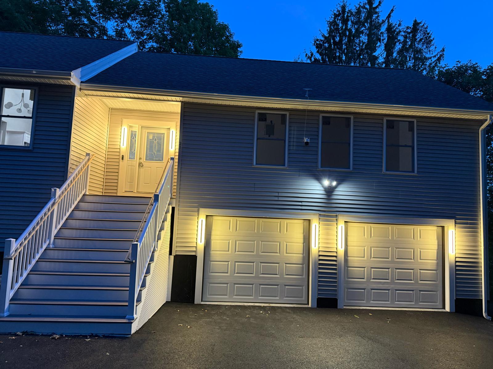 Exterior linear LED sconces installed around garage doors and front entry by Prime Light Electric LLC in Westborough MA