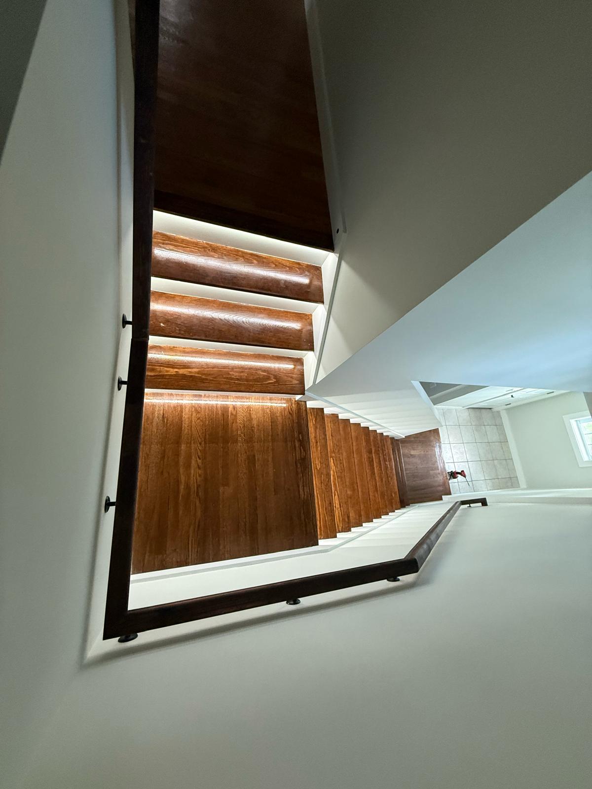 Concealed LED stair tread accent lighting installed on hardwood staircase by Prime Light Electric LLC in Grafton MA