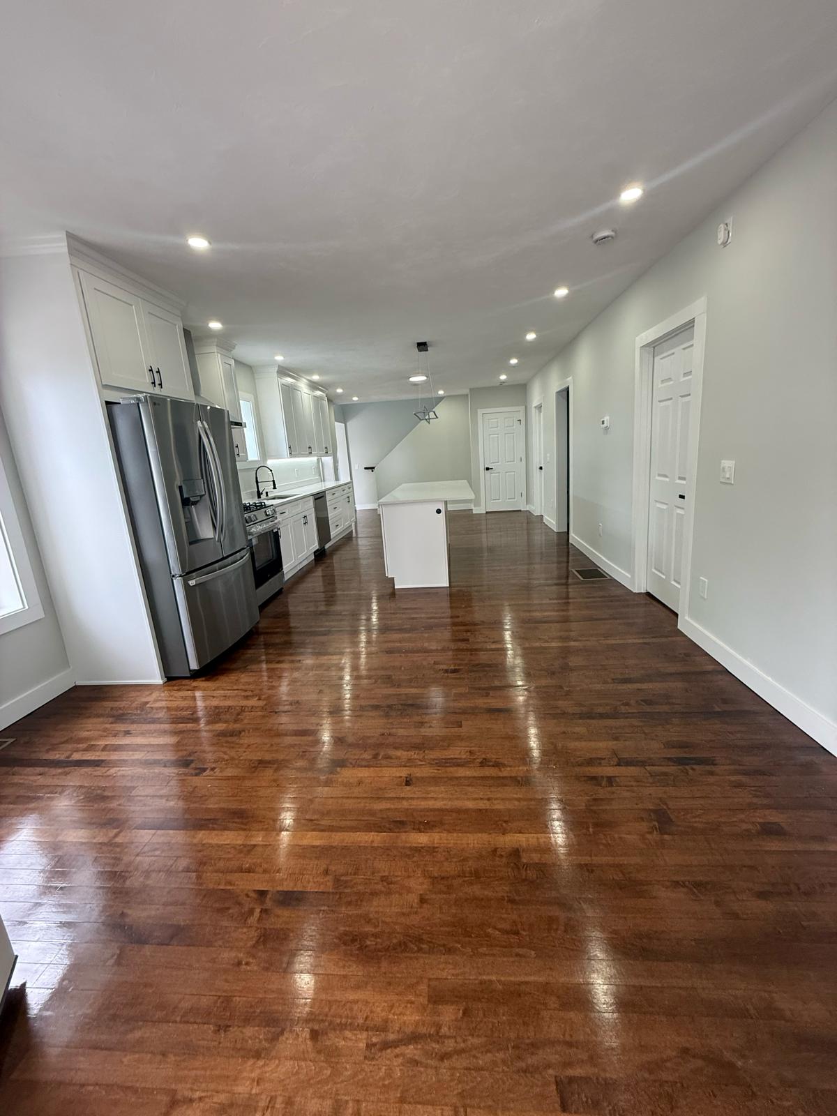 Finished open-concept kitchen and great room with recessed LED lighting and hardwood floors by Prime Light Electric LLC in Holden MA