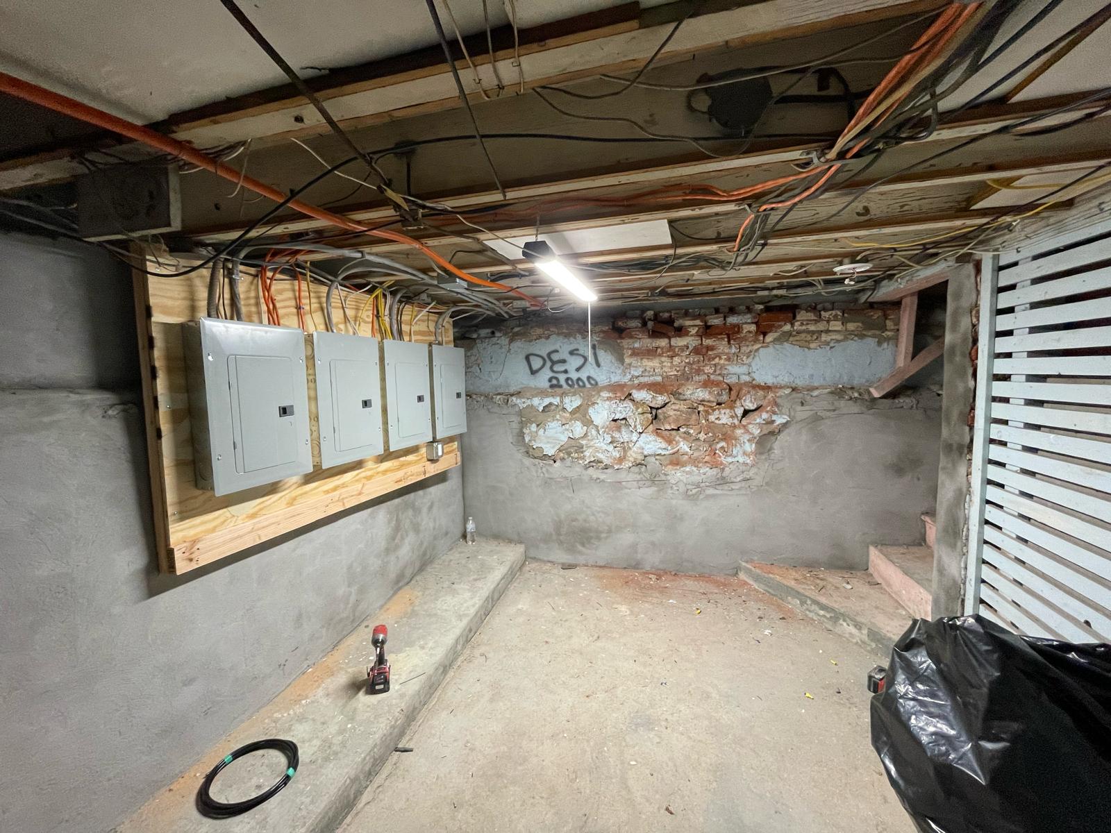 Four electrical breaker panels mounted on timber backing in Worcester MA basement by Prime Light Electric LLC