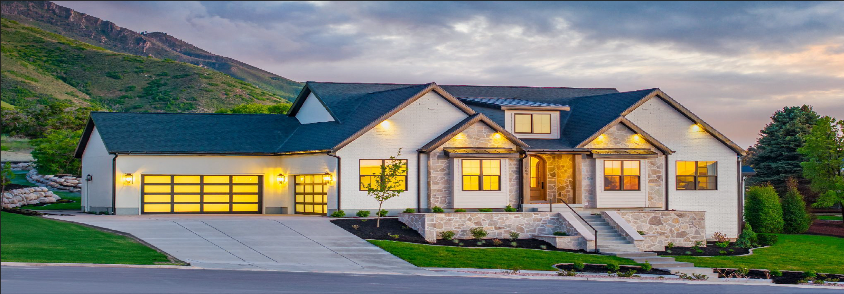 Luxury modern home with glowing warm lights and mountain backdrop