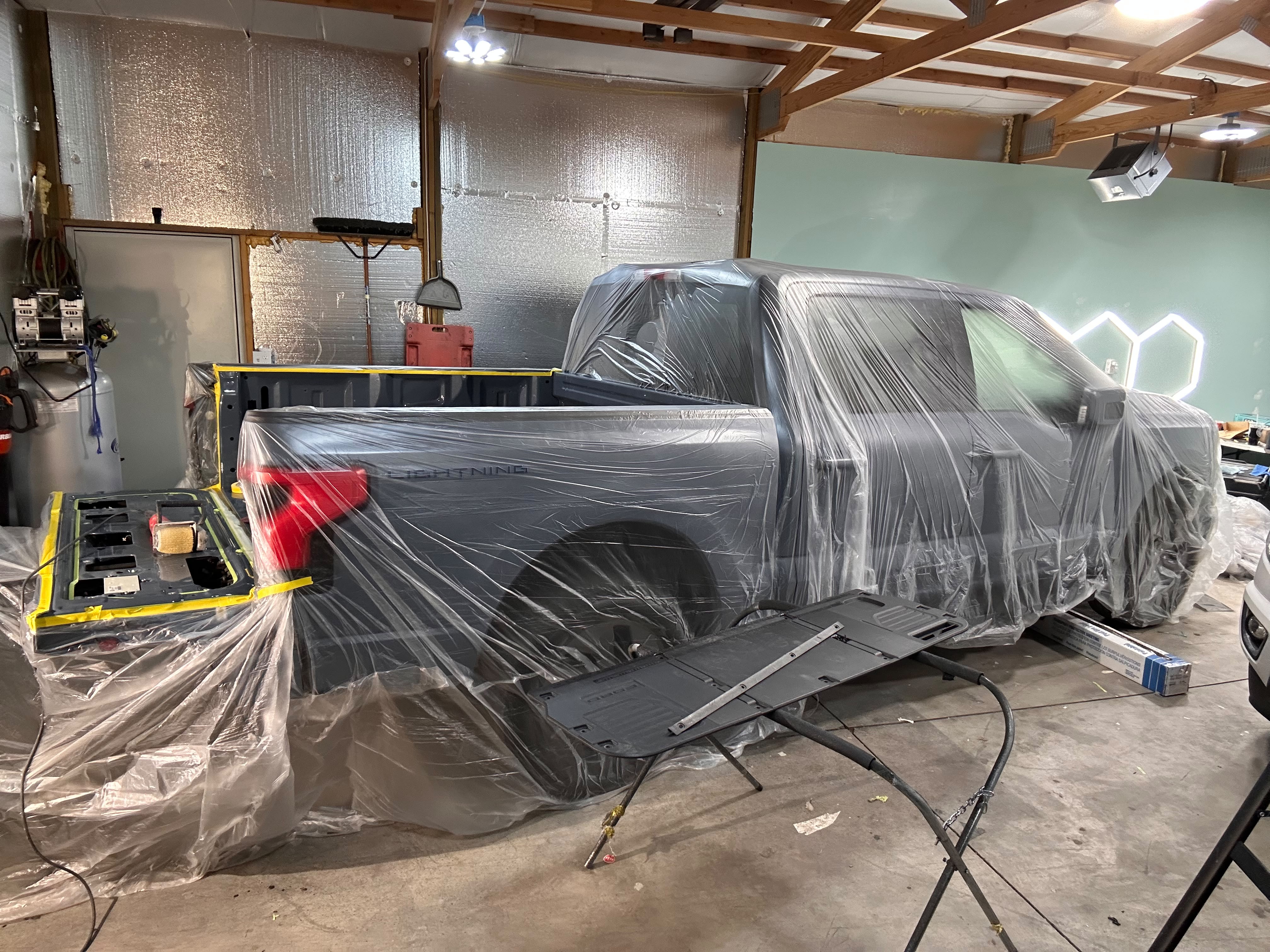 Ford F-150 Lightning electric pickup fully plastic-masked in shop bay for professional spray-in bed liner coating by Miracle Detailing Lindon UT