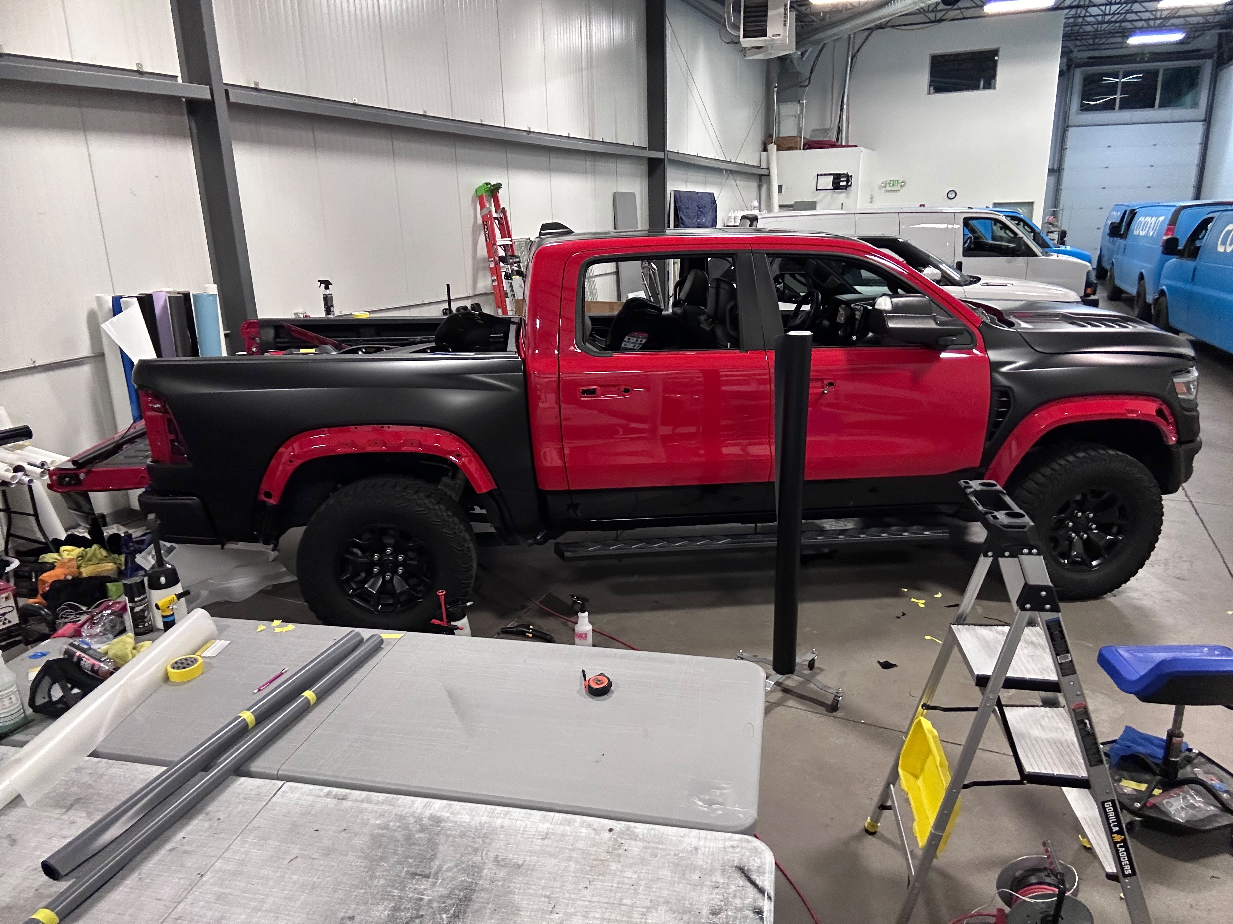 RAM TRX performance truck undergoing precision satin black vinyl wrap installation on truck bed and body panels in Miracle Detailing shop bay