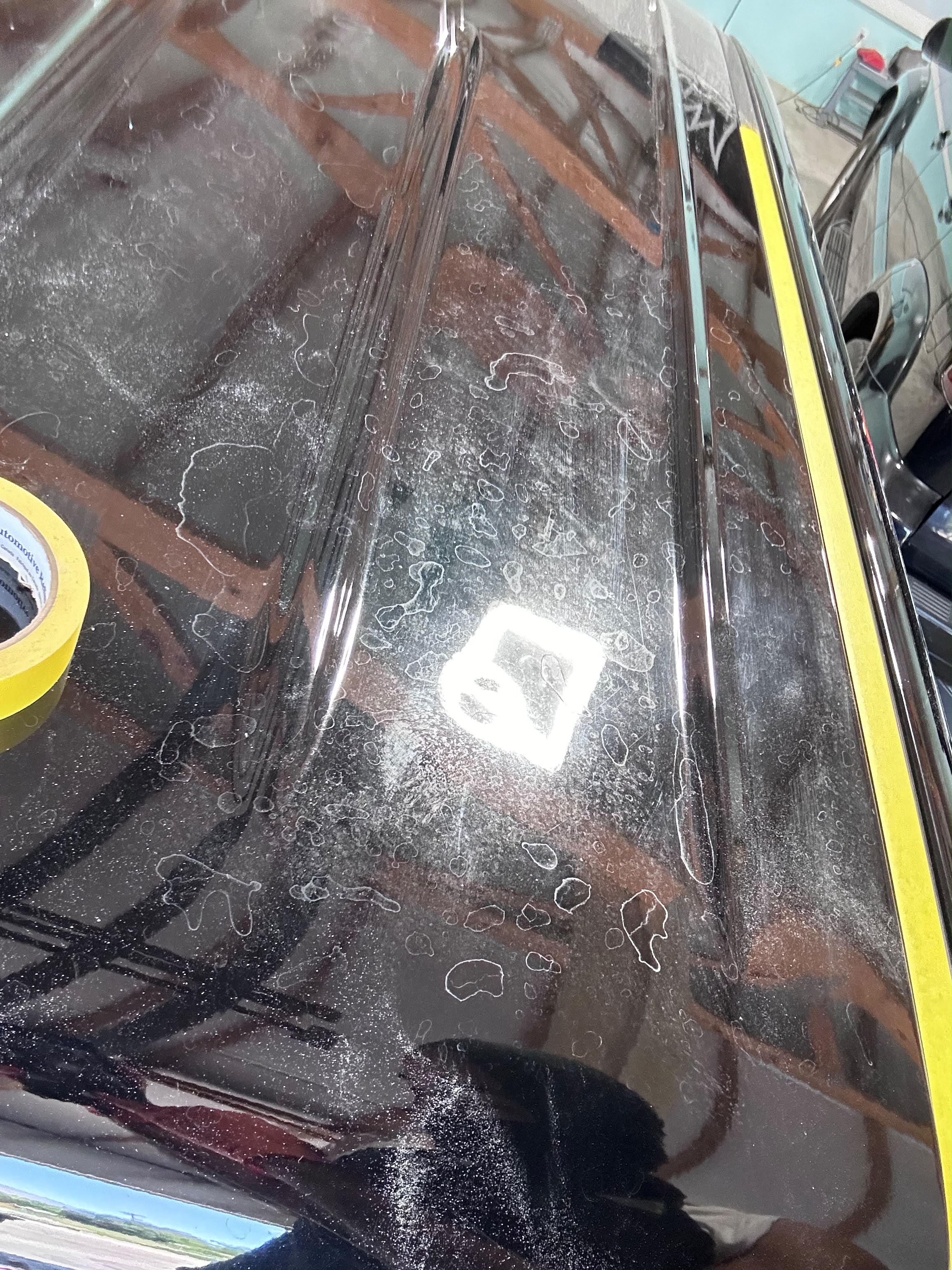 Vehicle roof covered in heavy mineral deposits and etched hard water rings prepped with yellow edge tape before paint correction by Miracle Detailing