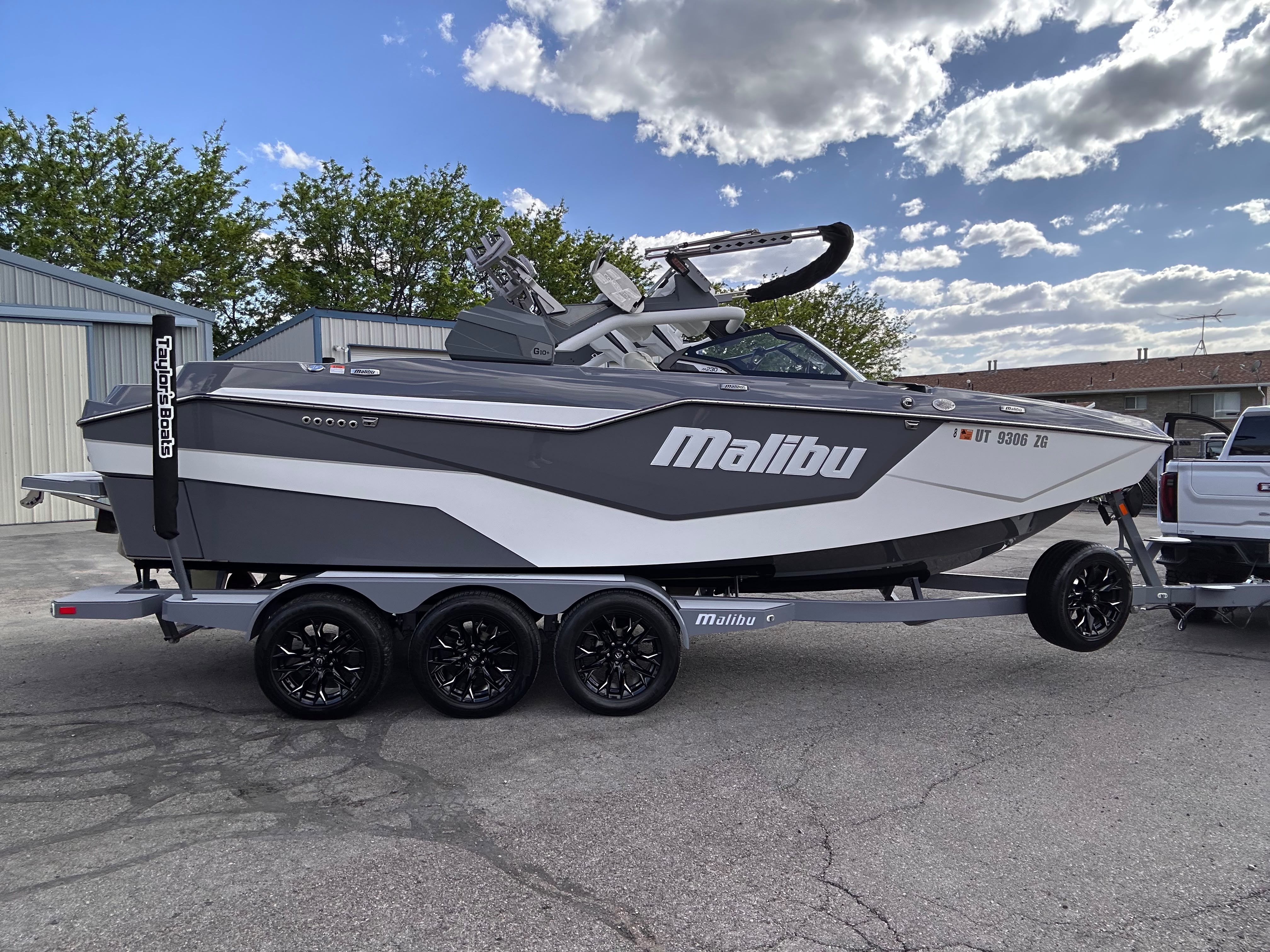 Malibu M230 wakeboard boat on tri-axle trailer after full gelcoat polish and marine ceramic protection outdoor sunlight by Miracle Detailing