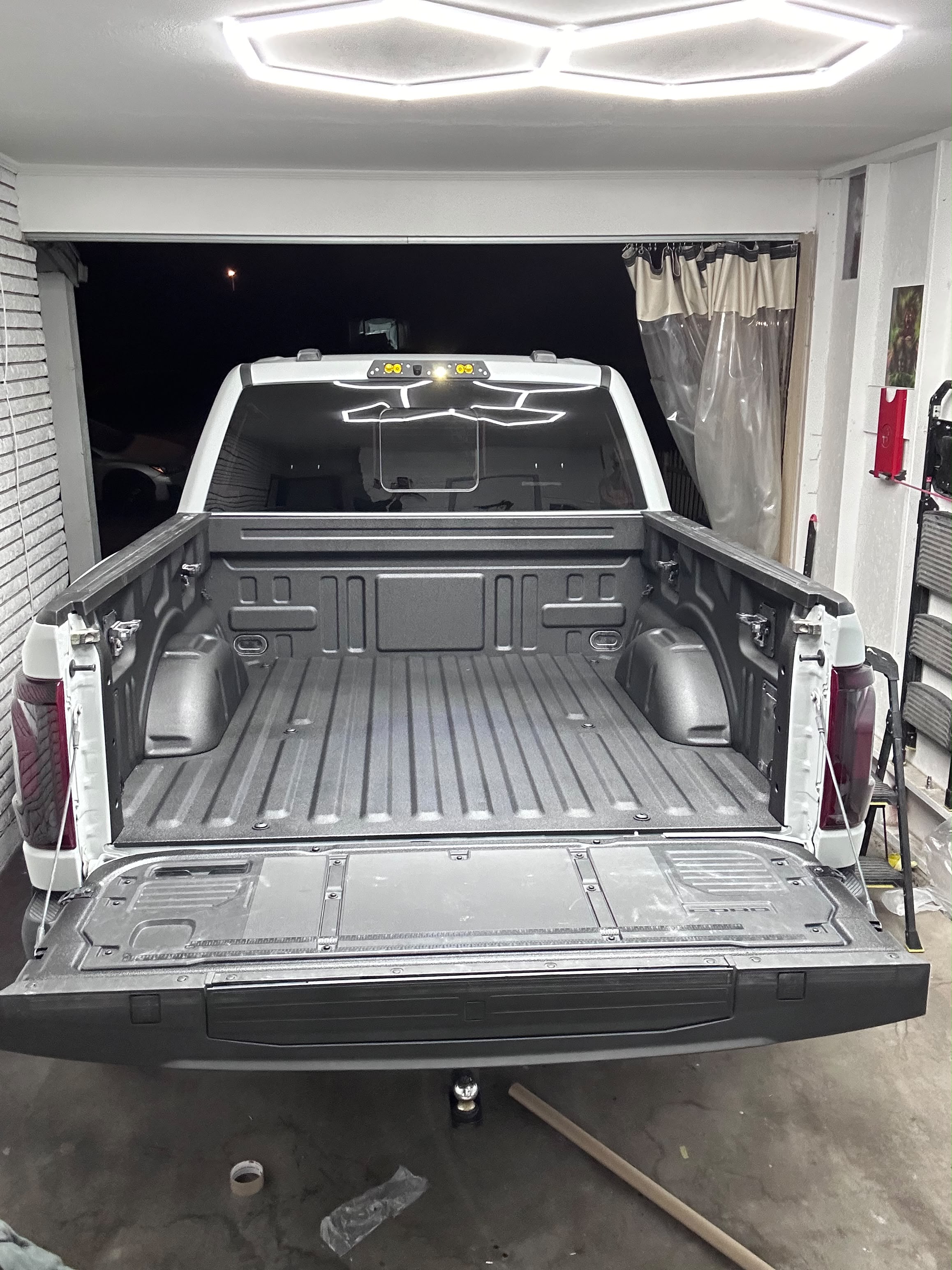Finished textured black spray-in bed liner on Ford truck under hexagon studio LED lighting by Miracle Detailing in Lindon UT