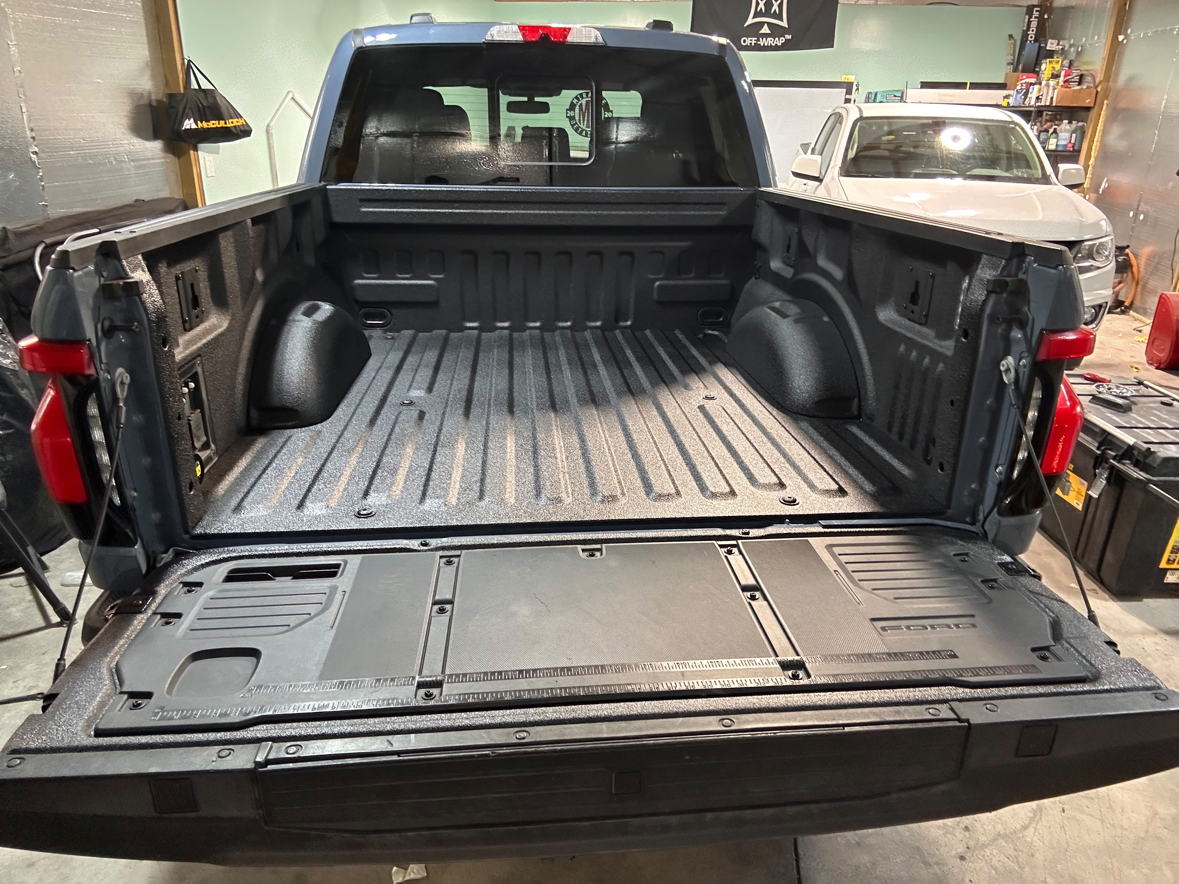 Ford F-150 truck bed and tailgate workstation protected with textured spray-in bed liner in shop bay by Miracle Detailing