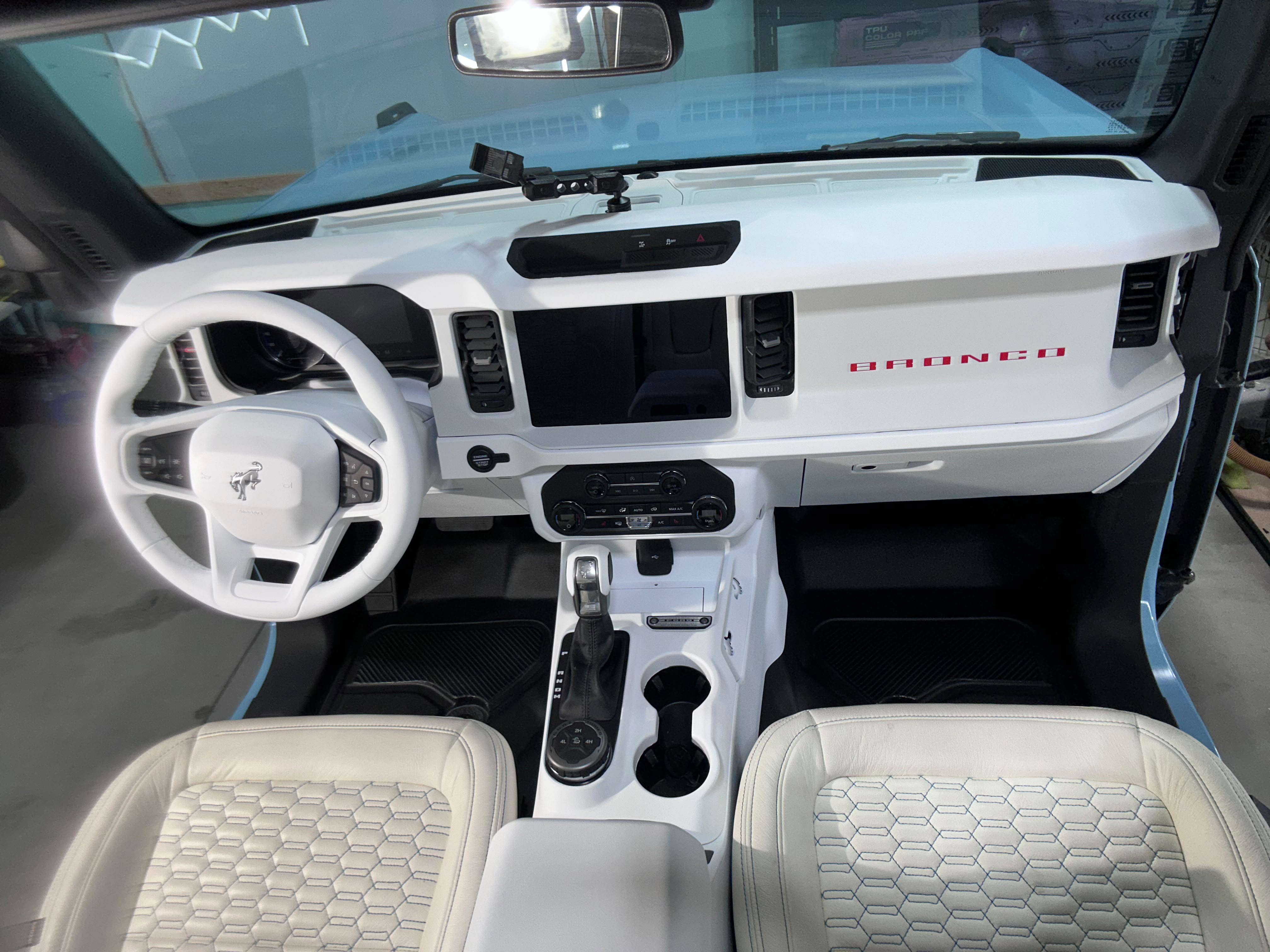 Wide cockpit view of Ford Bronco custom white interior trim and leather seats protected by Miracle Detailing in Lindon UT