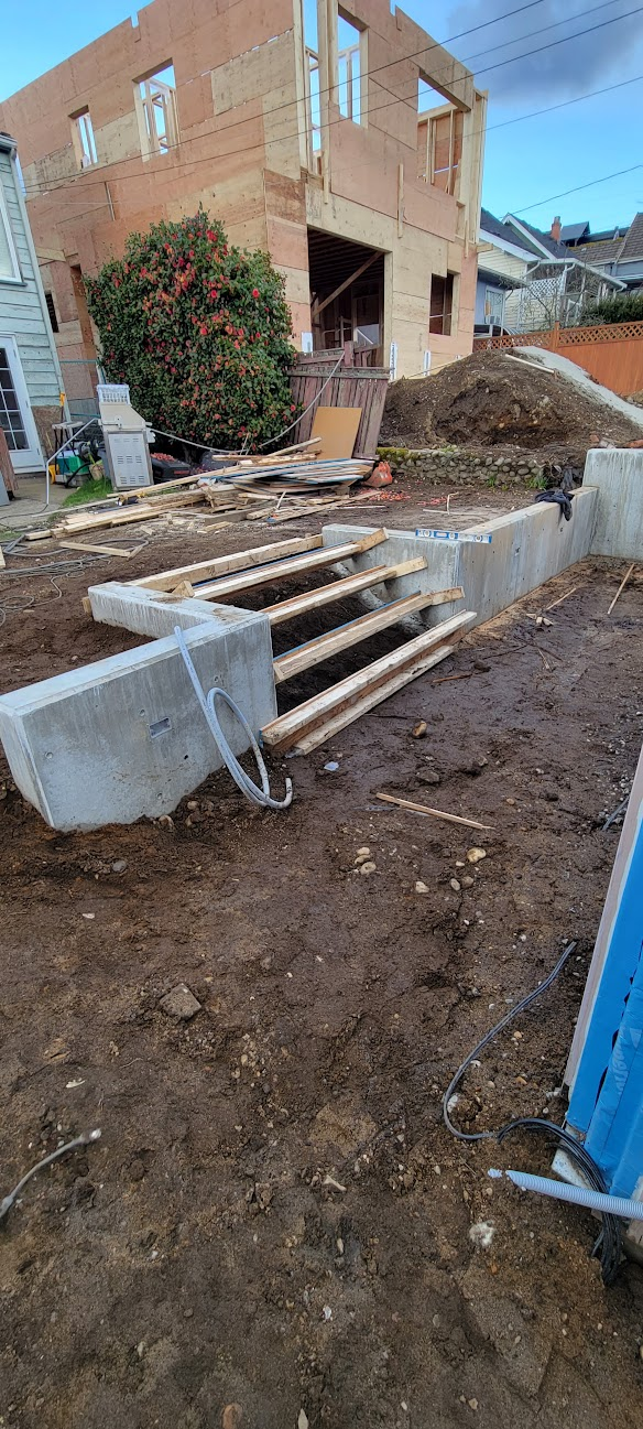 Residential poured concrete retaining wall with concrete stairs under construction.