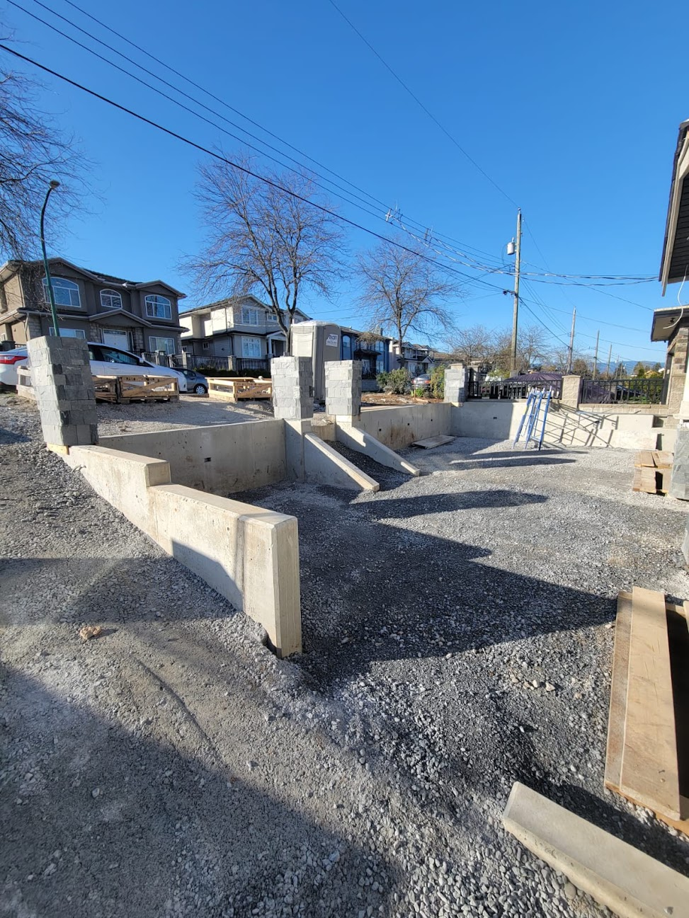 Large residential site with multiple poured concrete retaining walls and prepared base areas.