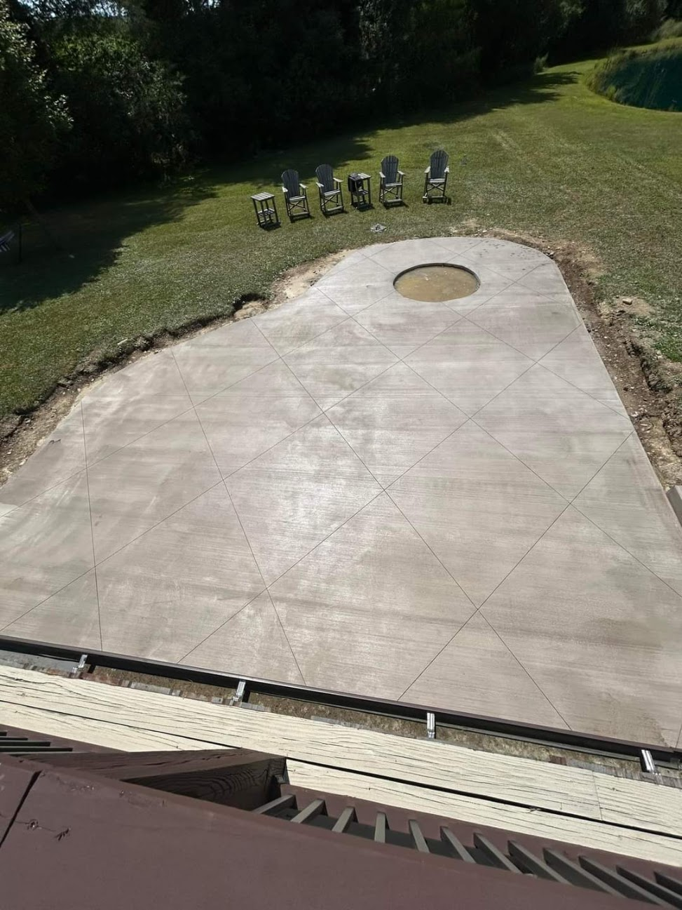 Large residential concrete patio with a circular opening for a fire-pit feature