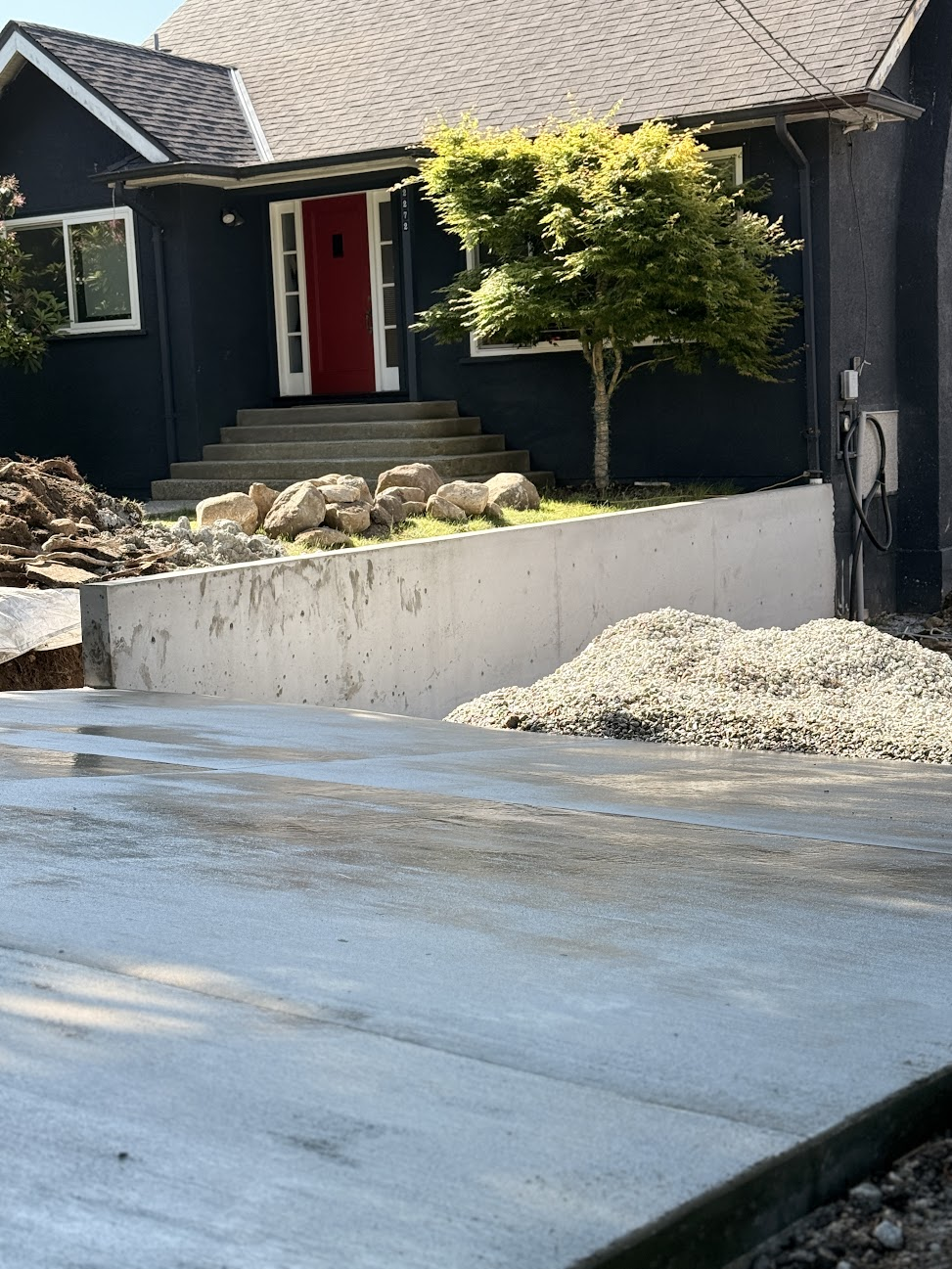 Finished poured concrete retaining wall beside a residential driveway and front entry.