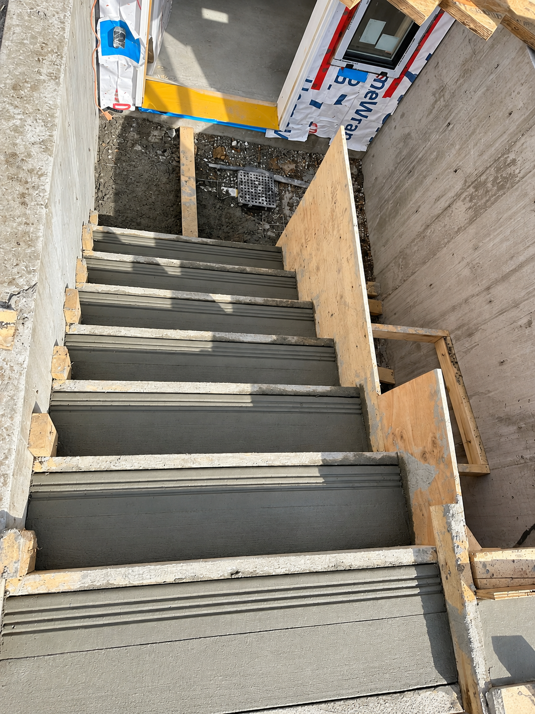 Finished front entry concrete stair system with decorative finish and black railings.