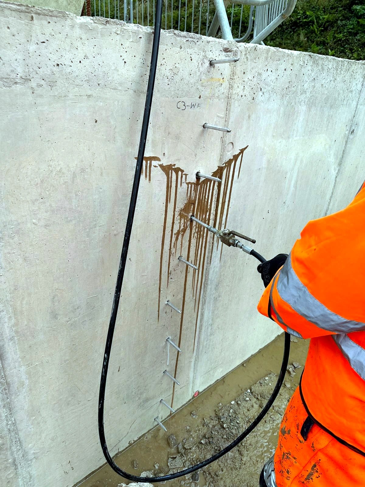 Mechanical injection ports installed along a cracked concrete wall during repair work