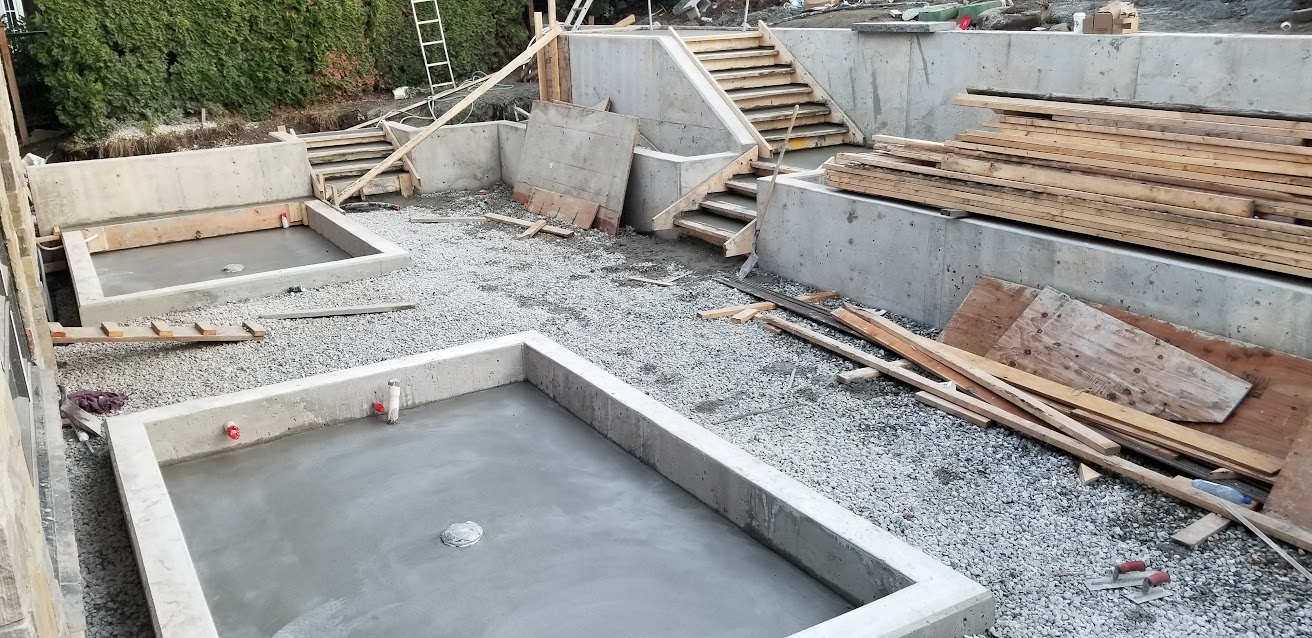 Poured concrete retaining walls and concrete steps across a multi-level residential site.