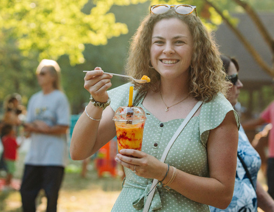 A festival attendee enjoying a shaved ice treat outdoors at a community festival at Sharon Woods