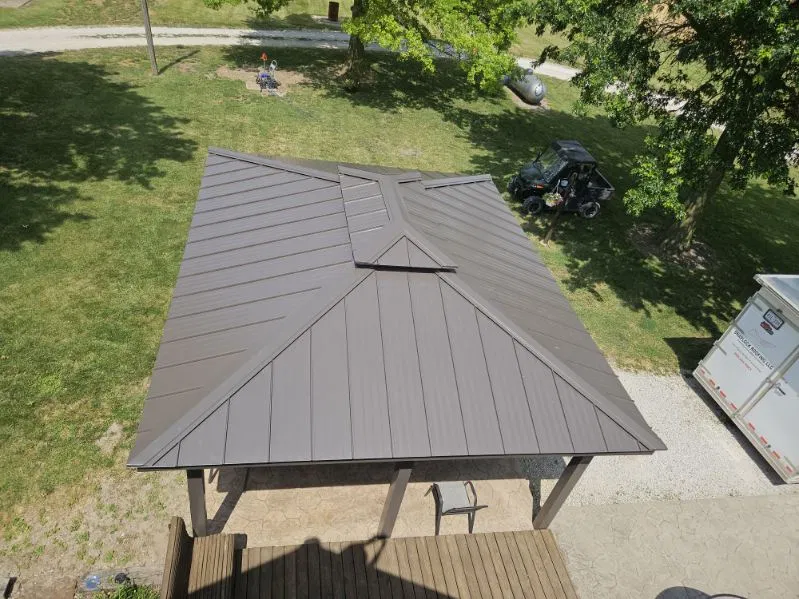 Overhead view of a bronze standing seam metal hip roof on a freestanding pavilion, with tapered panels on each hip, roll-formed on site by Snaplock Roofing LLC