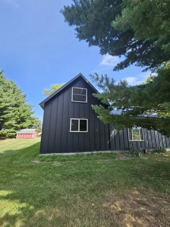 Gable end of a home clad in black board and batten steel siding, installed by Snaplock Roofing LLC