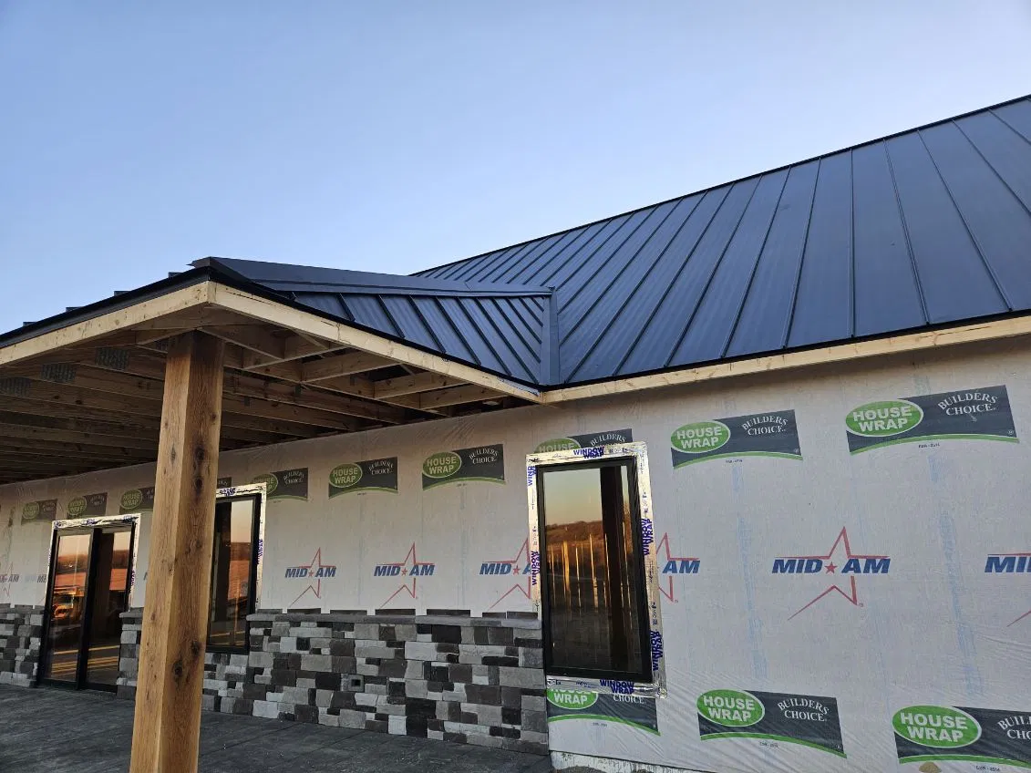 Close view of the eave, hip and seam terminations on a dark standing seam metal roof over a covered porch, installed by Snaplock Roofing LLC