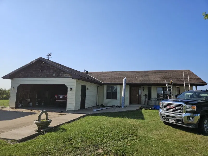 Cream ranch home with a worn brown shingle roof, with a ladder and roofing material staged on site at the start of a Snaplock Roofing LLC job
