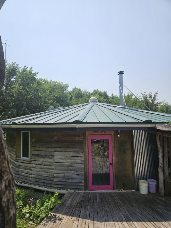 Round timber cabin with a green metal roof, roofed by Snaplock Roofing LLC