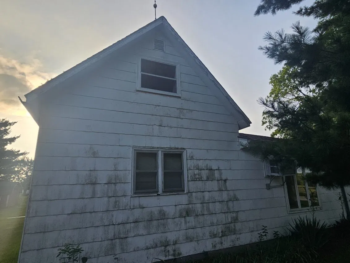 Weathered white farmhouse with peeling paint and an aging shingle roof before a Snaplock Roofing LLC roof replacement