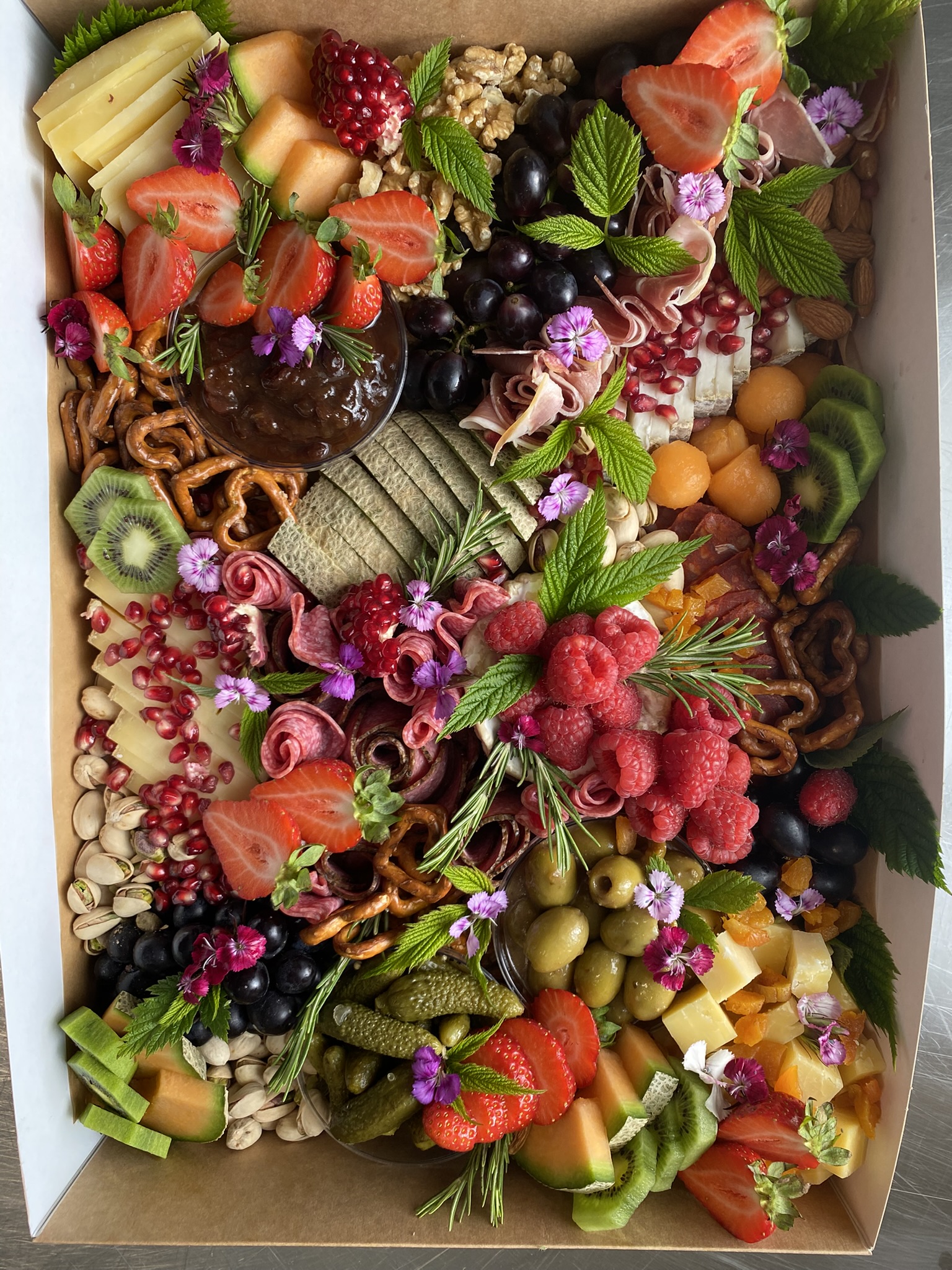 Abundant artisan charcuterie and fruit grazing box with berries and cheeses