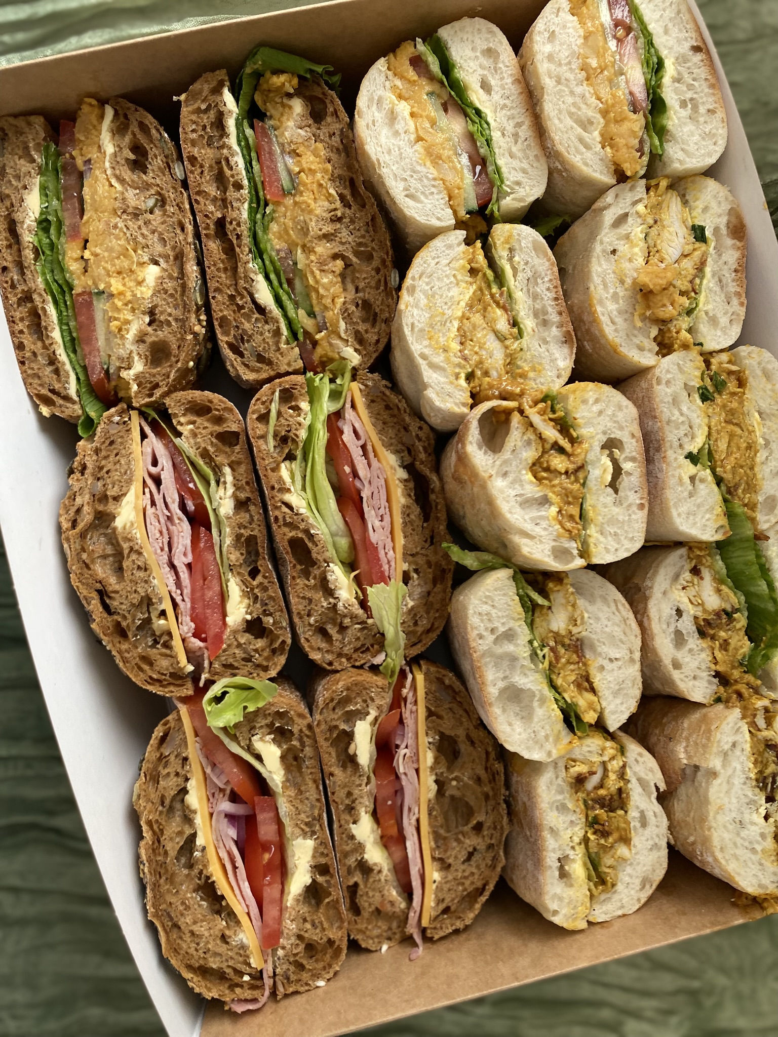 Fresh gourmet sandwich platter on rustic baguettes and artisan seeded breads by crumbelle