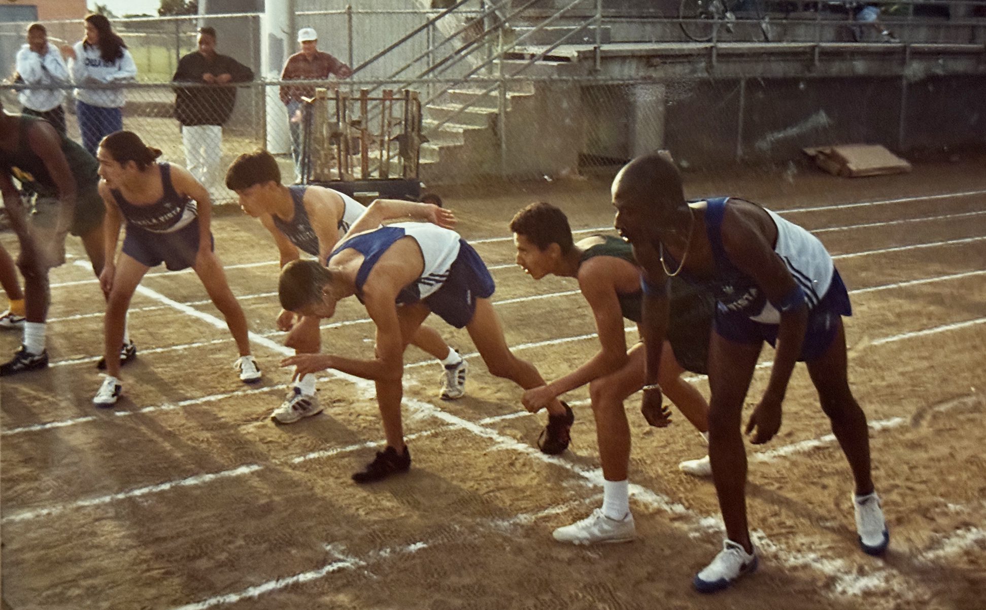 Coach Ken Nwadike Jr. competing on a dirt track starting line
