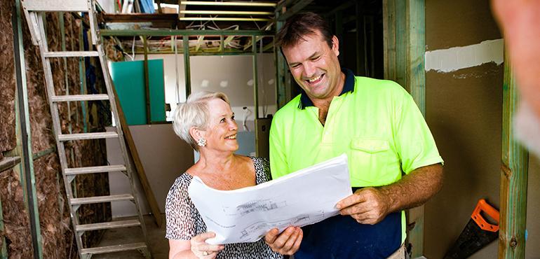 Homeowner and contractor reviewing architectural plans on site