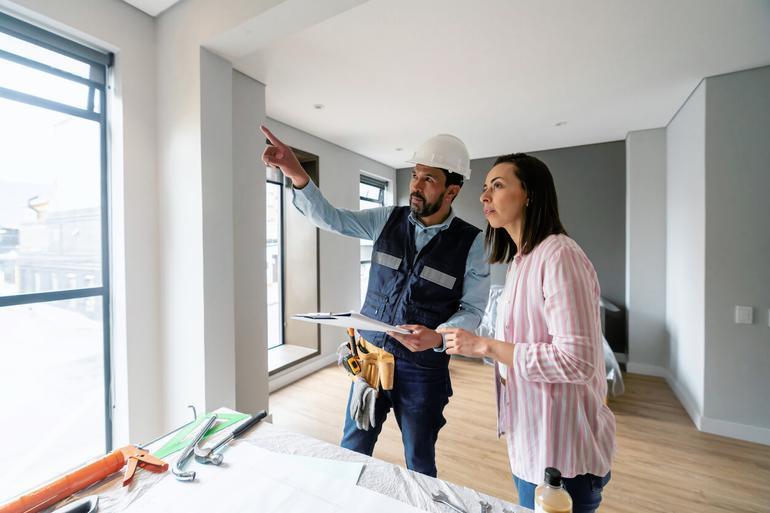 Builder in hard hat consulting with homeowner during home renovation
